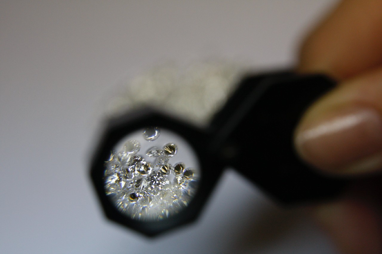 A jeweler observing small diamonds through a magnifying glass.