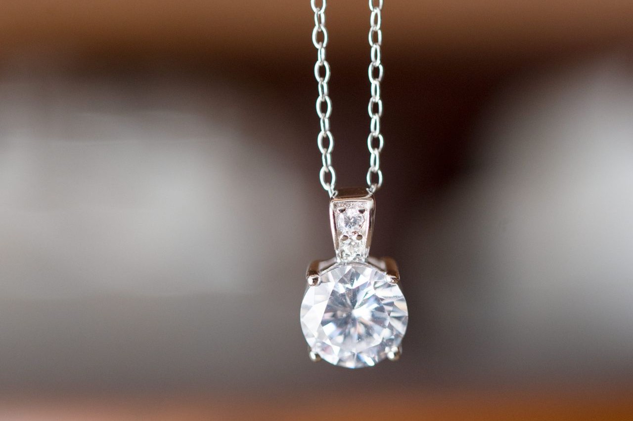 A round-cut diamond solitaire necklace is held by its sterling silver chain