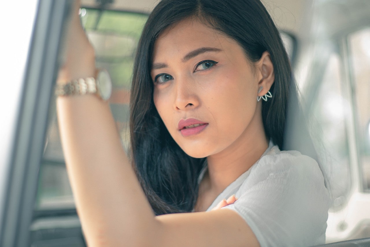 Woman sitting in a car wearing jewelry