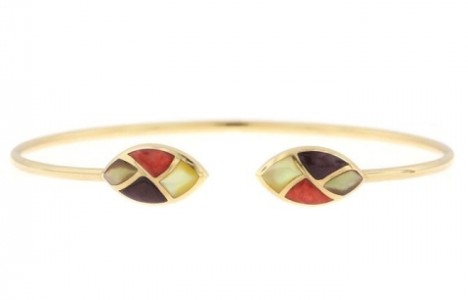 A thin, yellow gold cuff with four gemstones fashioned into a leaf motif before the space in the design by Kabana