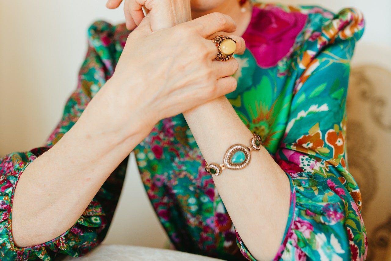 a woman in a brightly patterned blouse wearing a turquoise bracelet