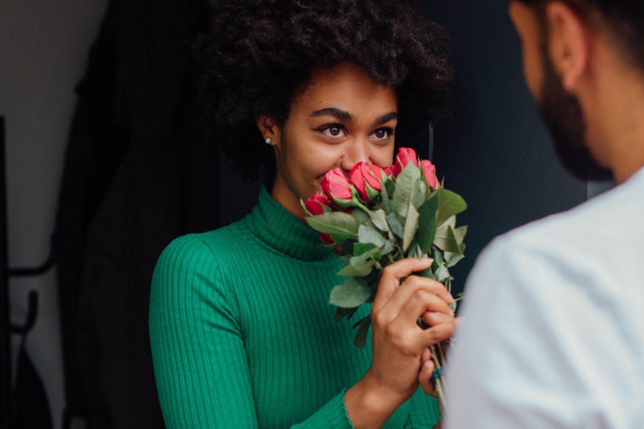 a woman sniffs roses that her Valentine’s Day date brought for her.