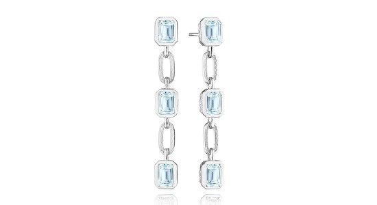 a pair of white gold drop earrings featuring light blue bezel set gemstones