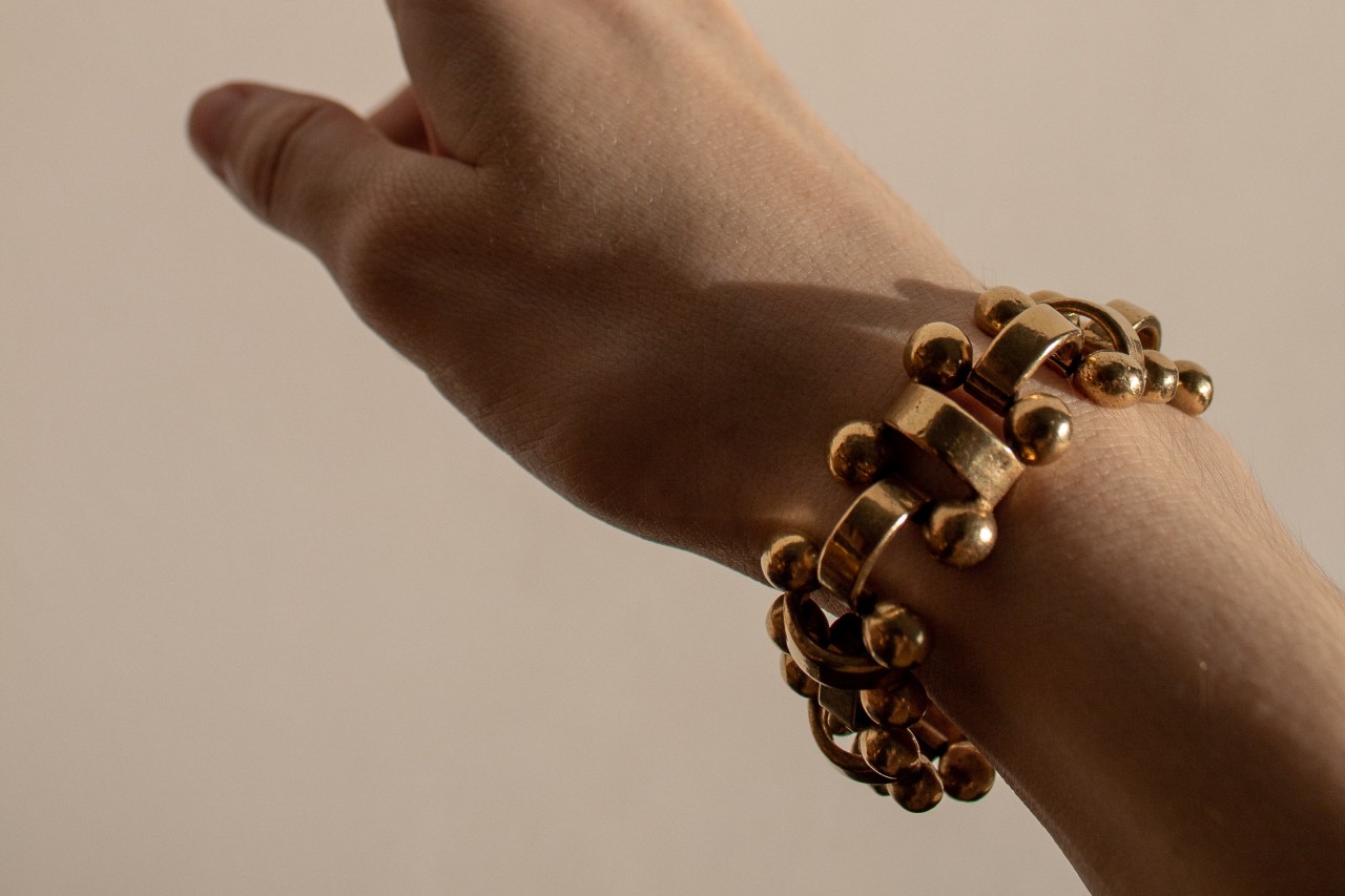 an outstretched hand wearing a chunky gold bracelet
