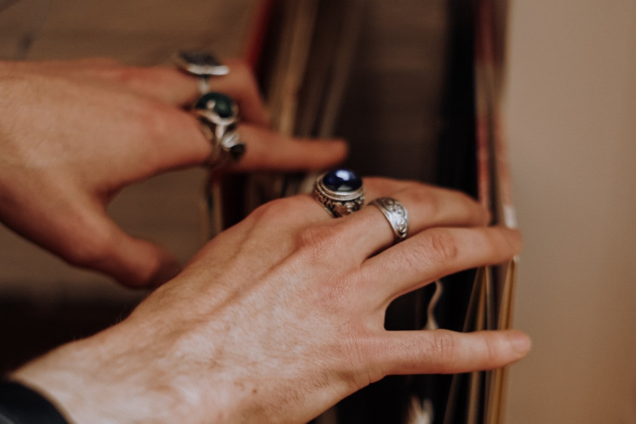 A person’s hands, adorned with multiple silver fashion rings, sorting through records.