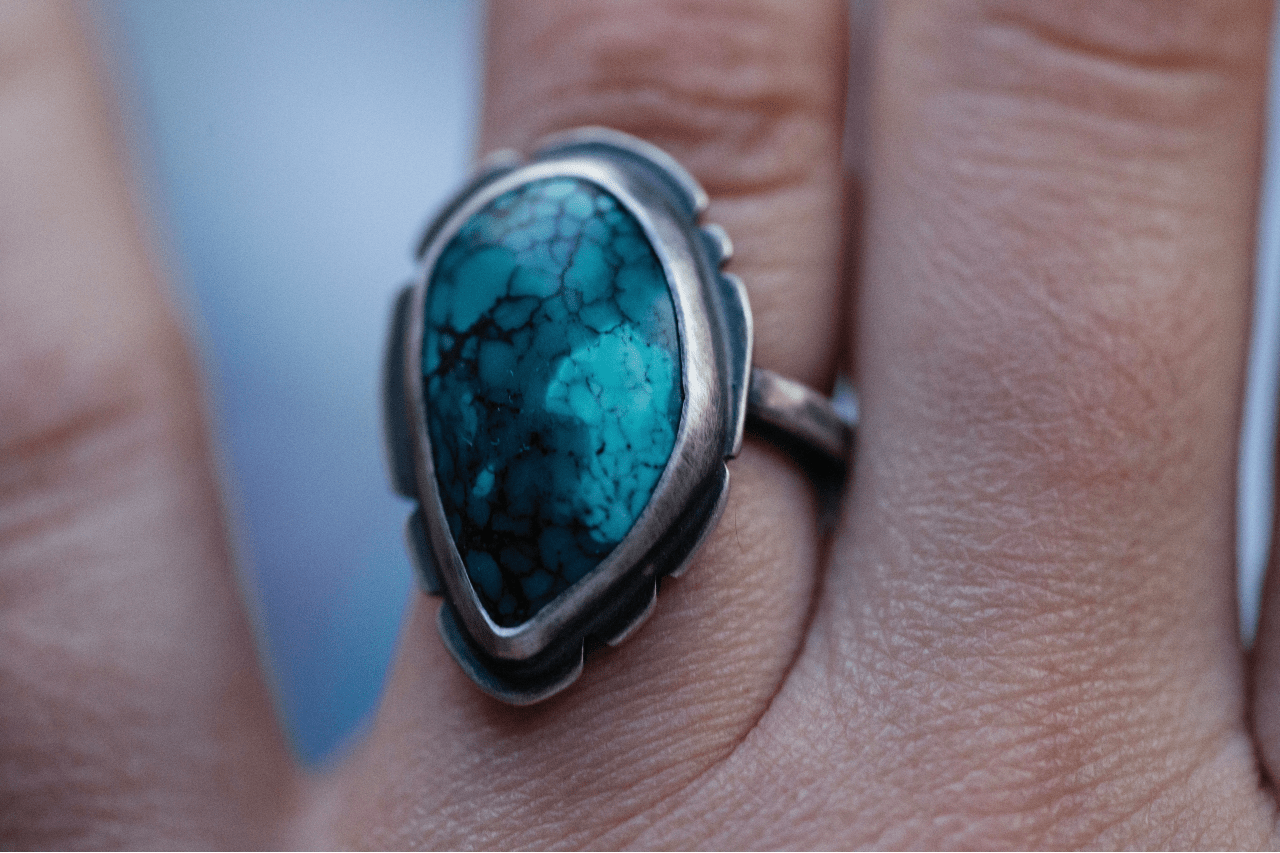 close up image of a silver and turquoise ring on a person’s hand