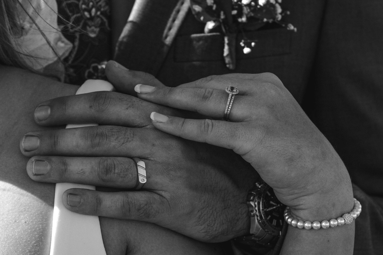 A black and white photo of a bride and groom, both wearing bridal rings.