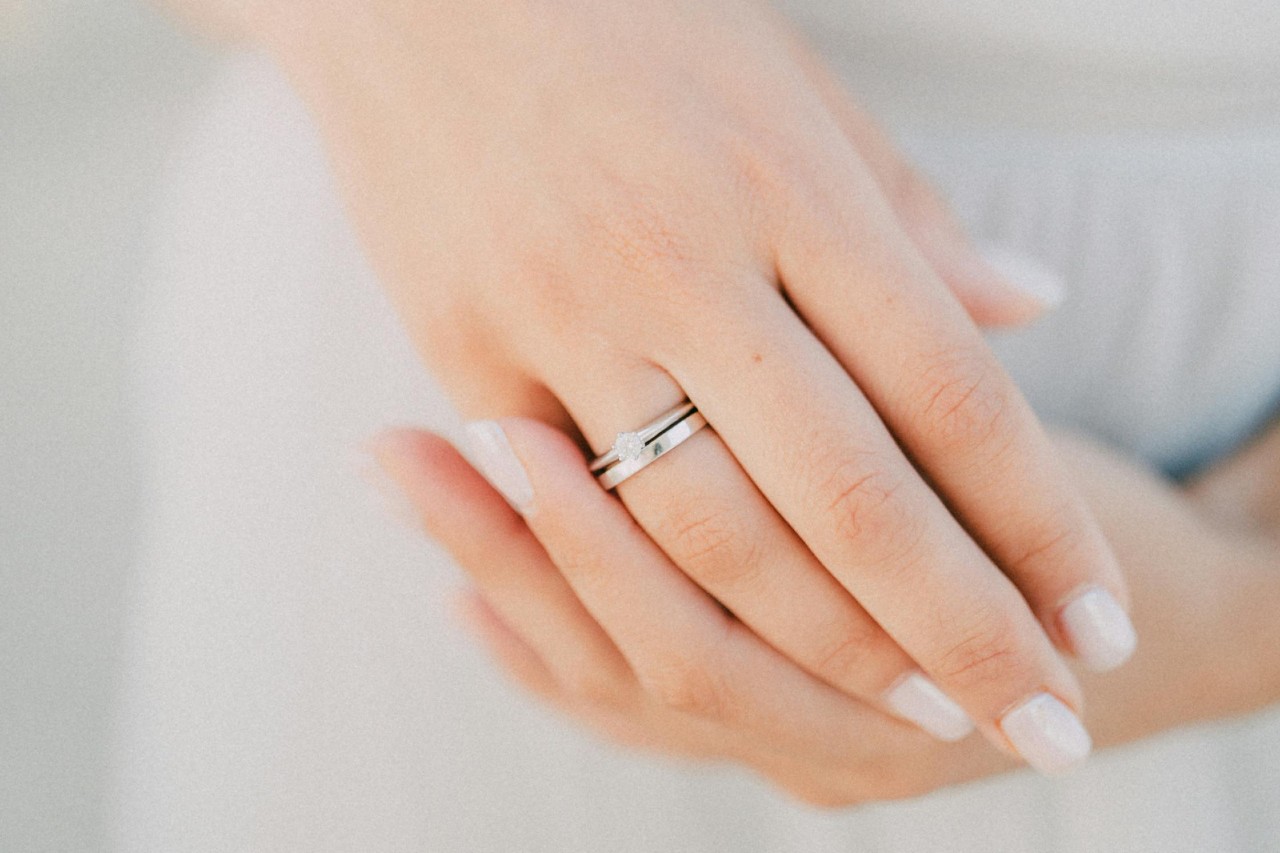 A bride wearing a simple engagement ring and wedding band matching set.