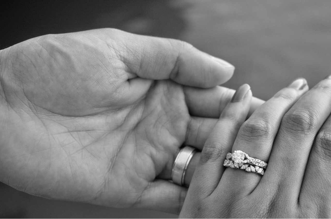 black and white photo of a bride and groom holding hands and showing off their bridal rings