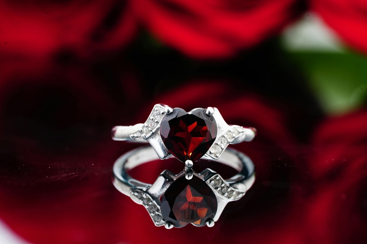 a white gold fashion ring featuring a heart cut ruby and diamond accents