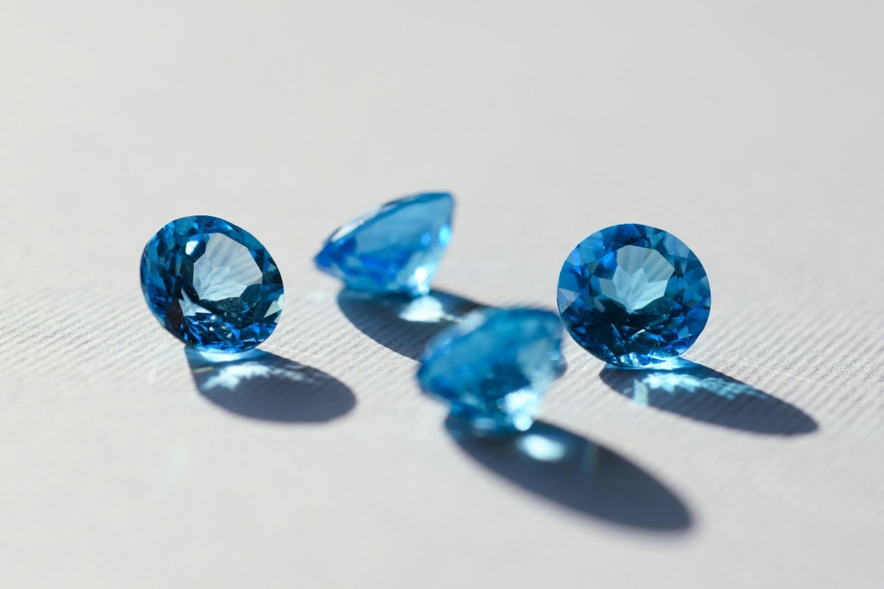 four round cut light blue gemstones sitting on a white surface